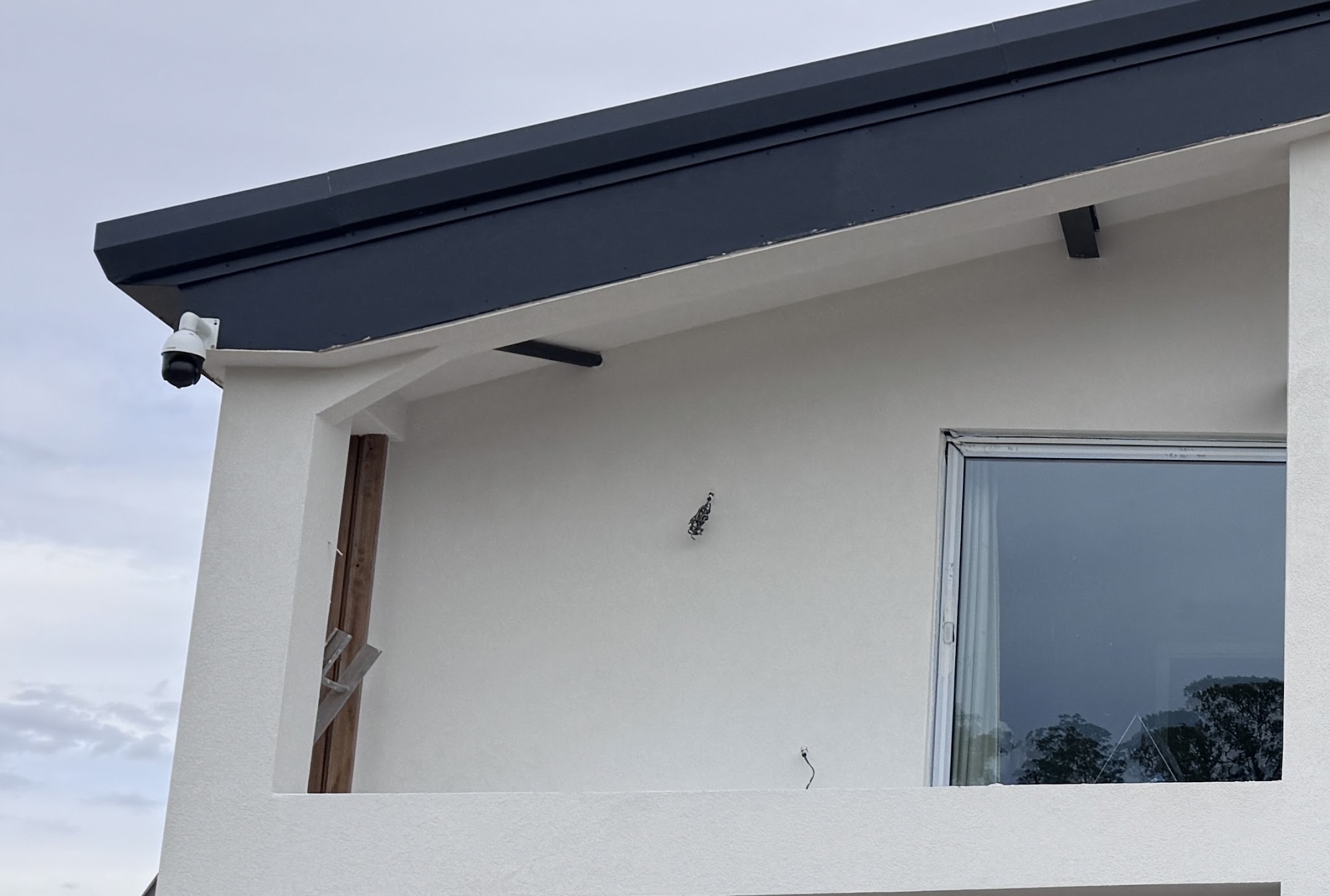 White render on the back of a house under a dark fascia