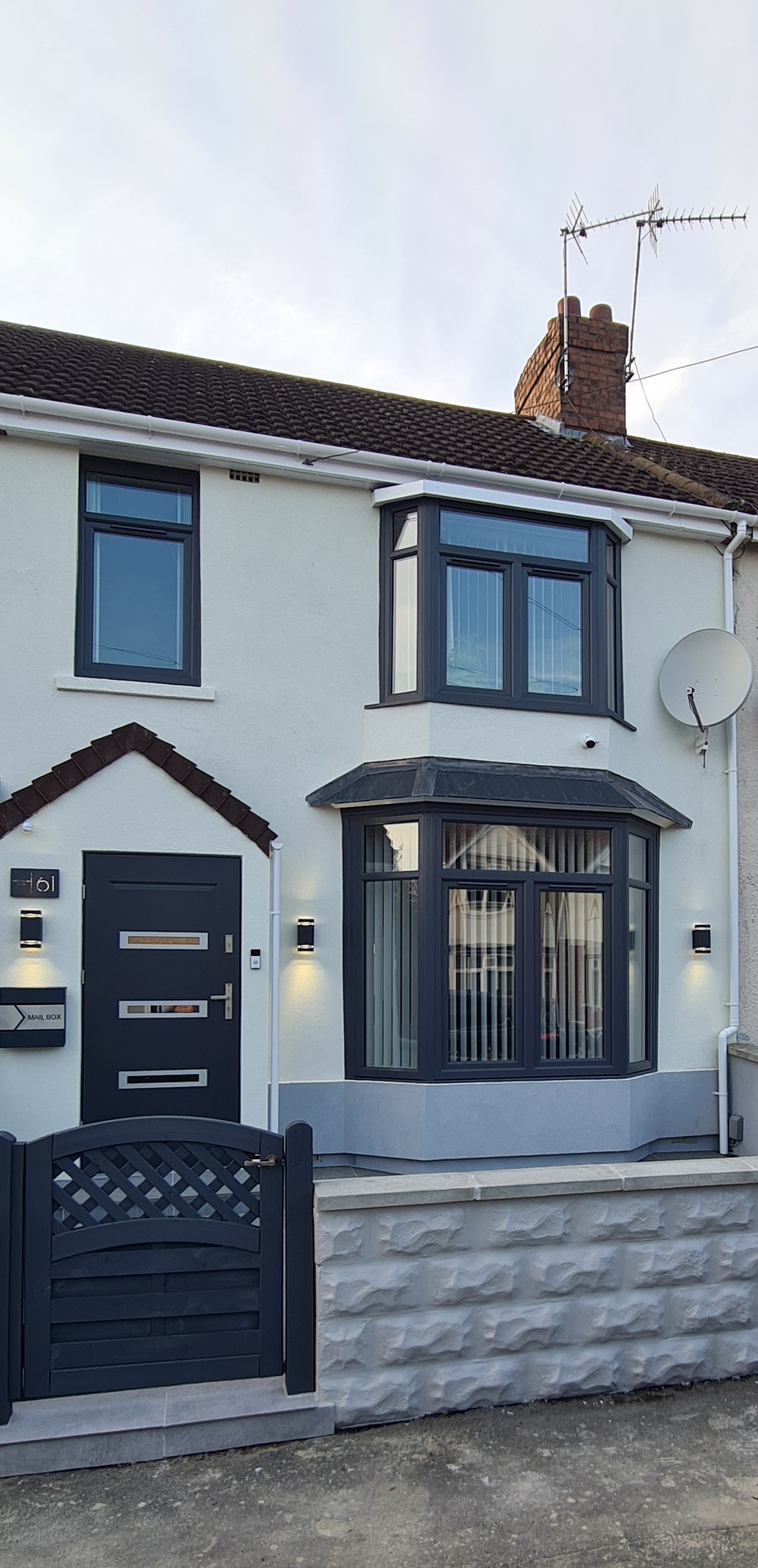 White rendered terraced house front with dark grey windows