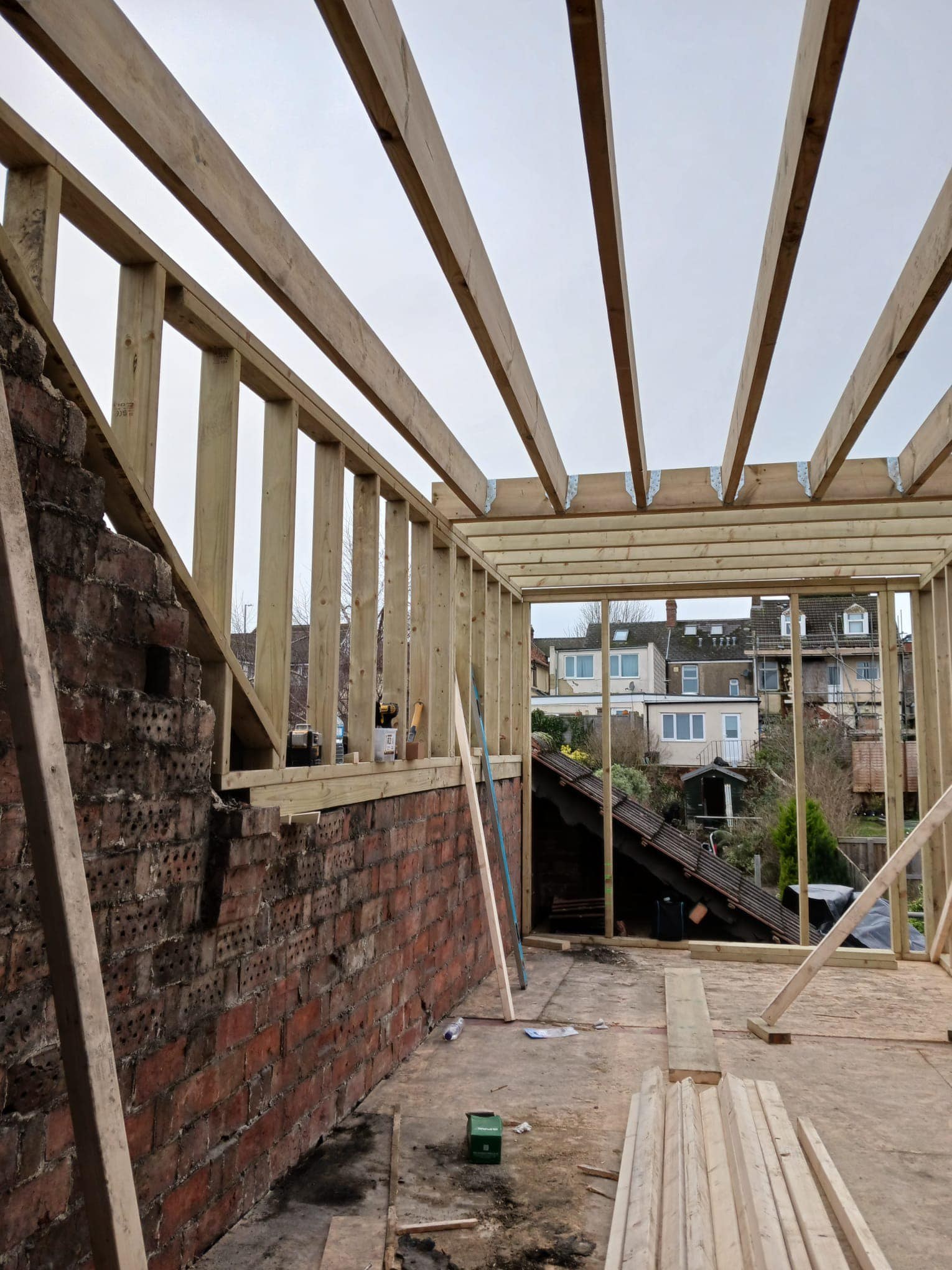 Timber-framed extension going up against an old brick wall
