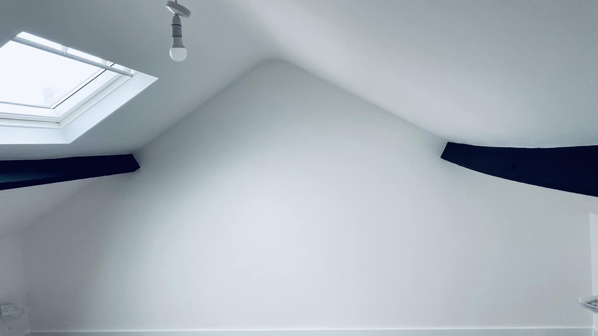 The same loft room finished in white under the roof window
