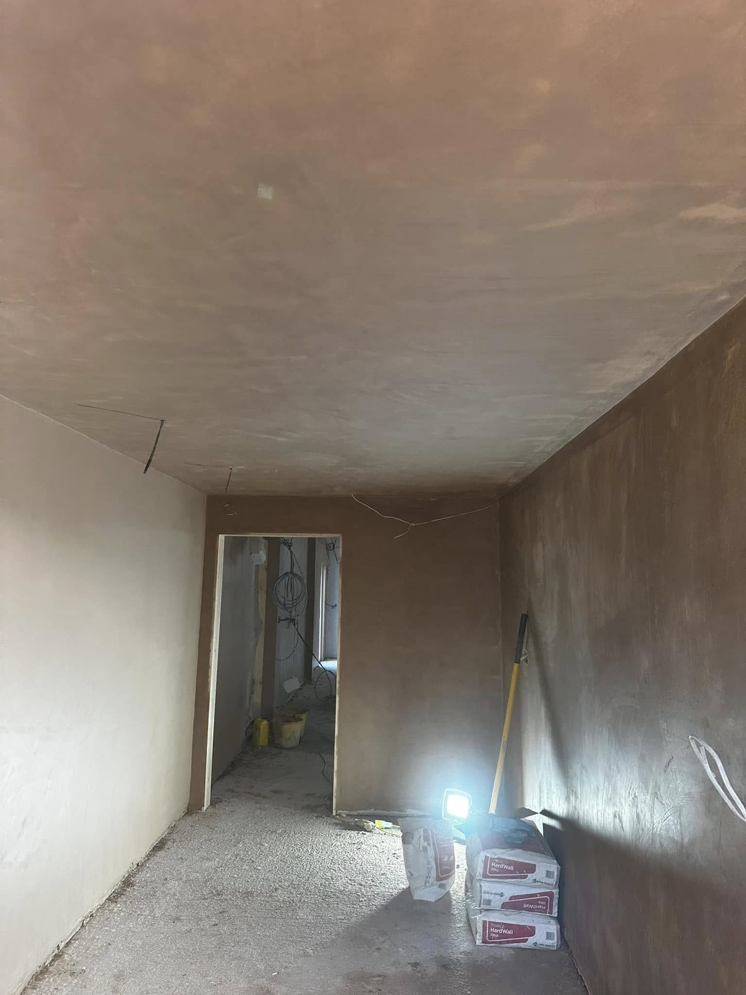 Long corridor freshly plastered, lit by a site lamp